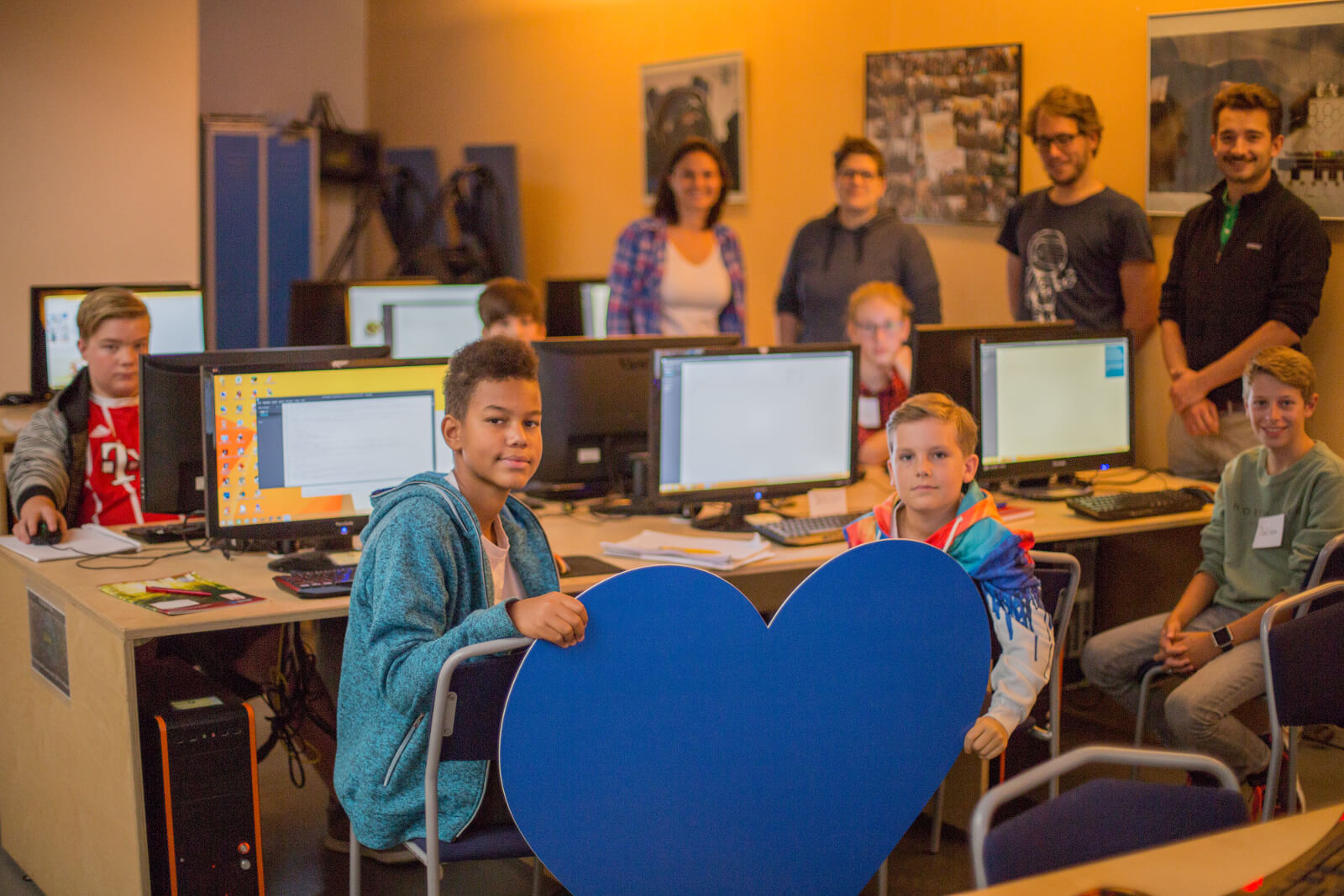 Eine Gruppe von Kindern mit Trainern im Hintergrund, die am Computer arbeiten. 